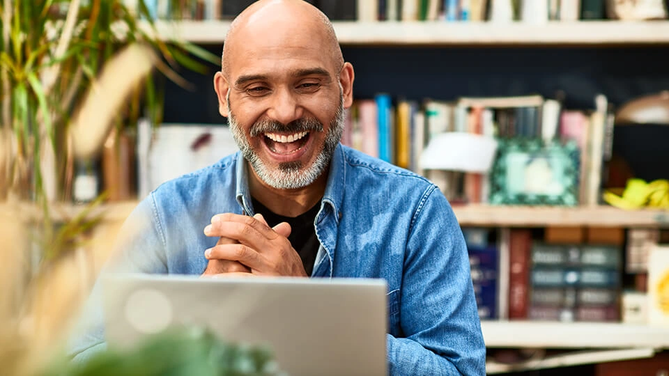 a man with a big smile looking at a laptop