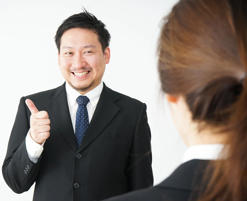 Male Employee who is smiling looking at his boss and holding up his thumb.